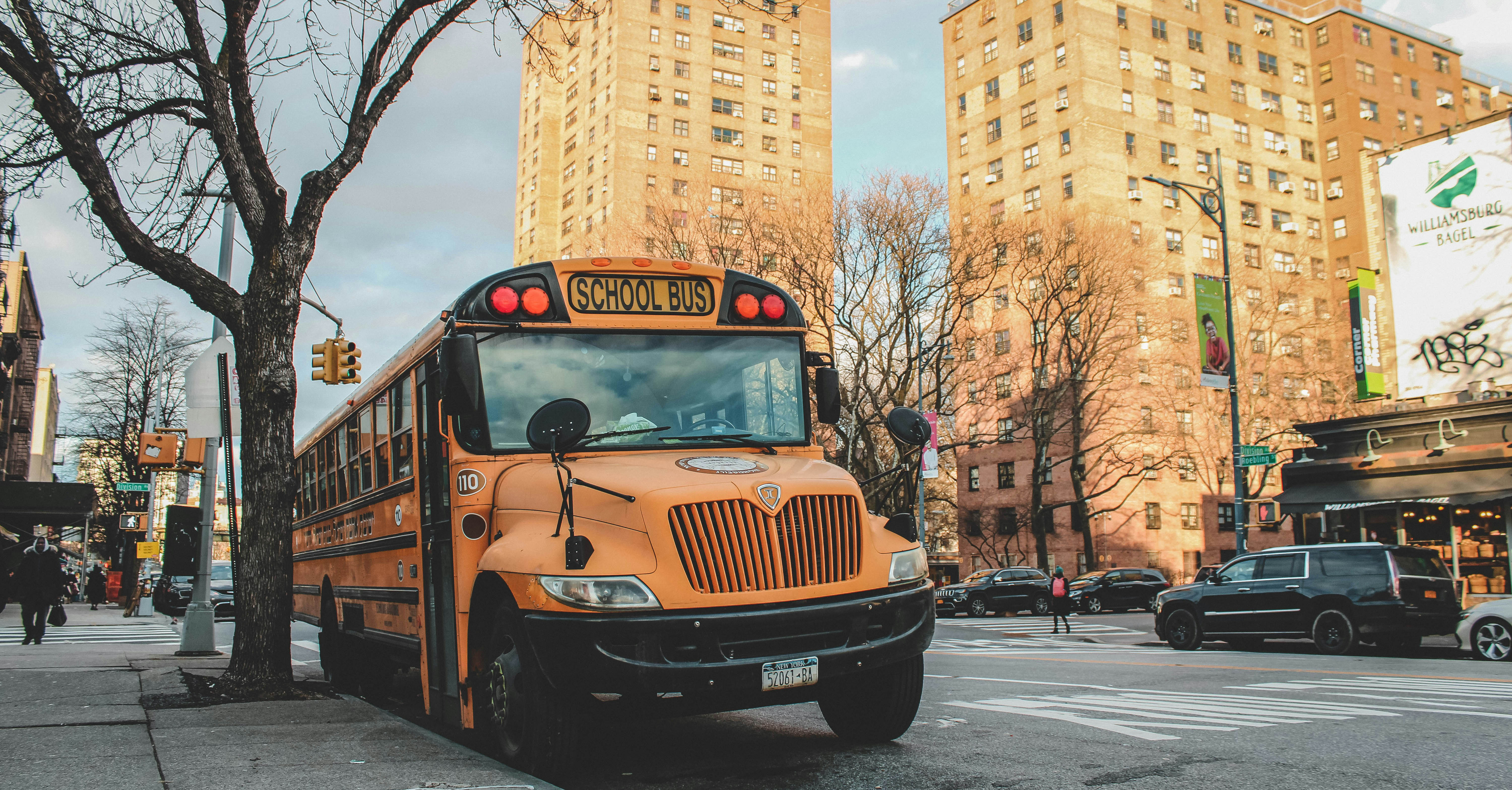 A school bus sits parked on the the side of a busy New York City street.