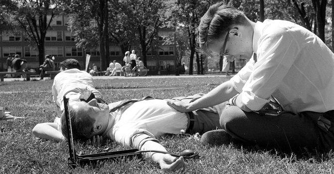 Students practice taking blood pressure on the campus lawn, May 1958. © Regents of the University of Michigan.