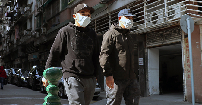 Two men walk down a street in Macau wearing face masks to protect them to be infected with coronavirus.