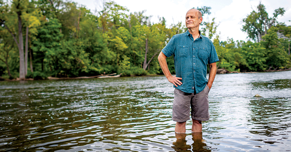 Joe Eisenberg in the Huron River observing the interplay of natural ecosystems and human-built environments. Eisenberg is professor of Epidemiology and Global Public Health, School of Public Health, University of Michigan