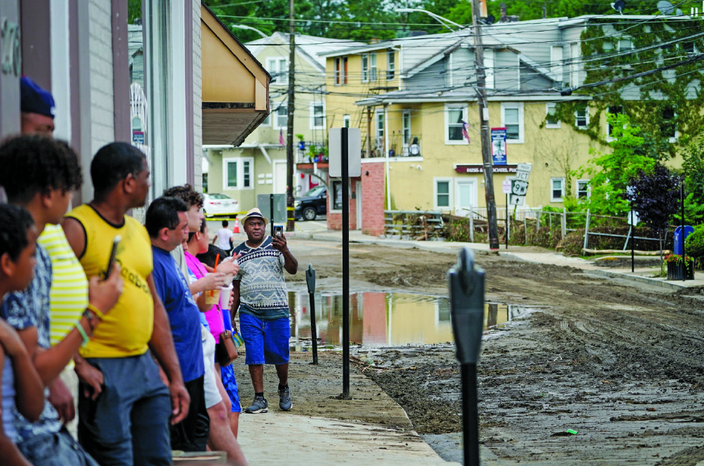 On July 10, 2023, pedestrians line Main Street in Highland Falls, New York, after flood waters receded. A storm washed out roads the previous day.