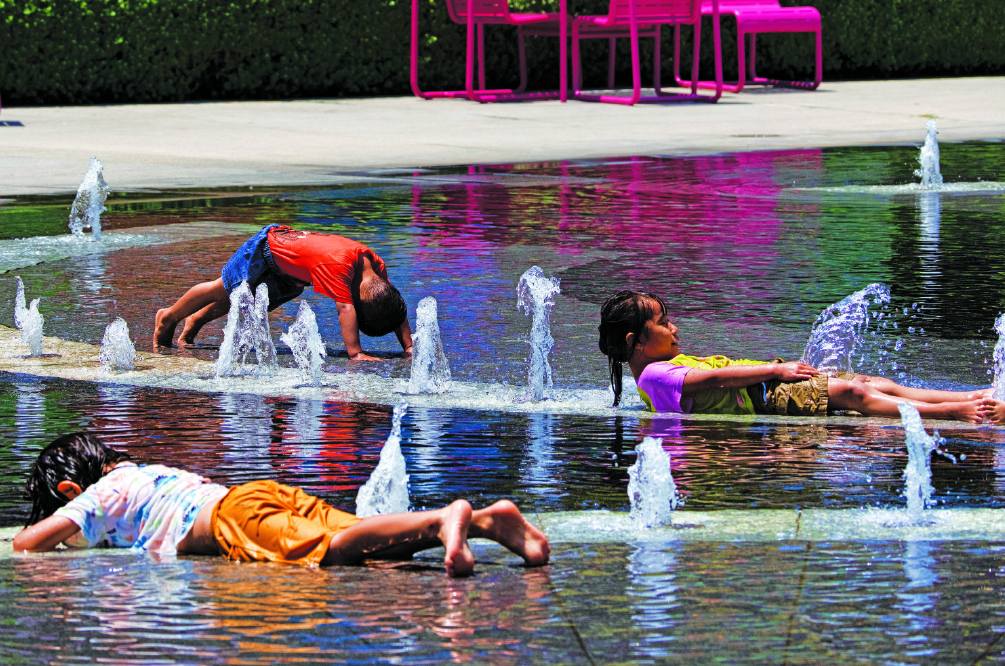 Kids use a city fountain in downtown Los Angeles to cool off on July 16, 2023. This summer, heat records were shattered across the US.