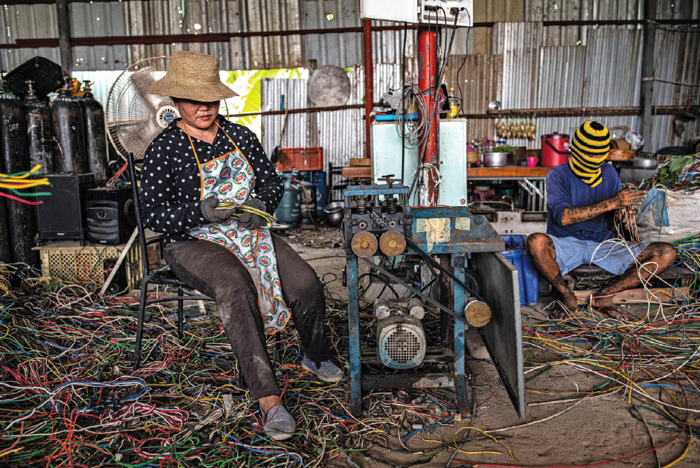 Workers break down wire to extract its copper in an e-waste recycling workshop located on the outskirts of Bangkok in 2019.