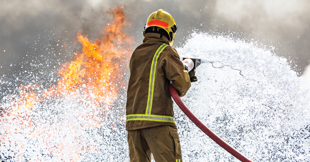 A firefighter putting out a fire with foam