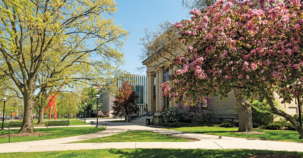 Trees bloom on central campus outside the University of Michigan Museum of Art, with Angell Hall and Mark di Suvero’s Orion sculpture in the background.