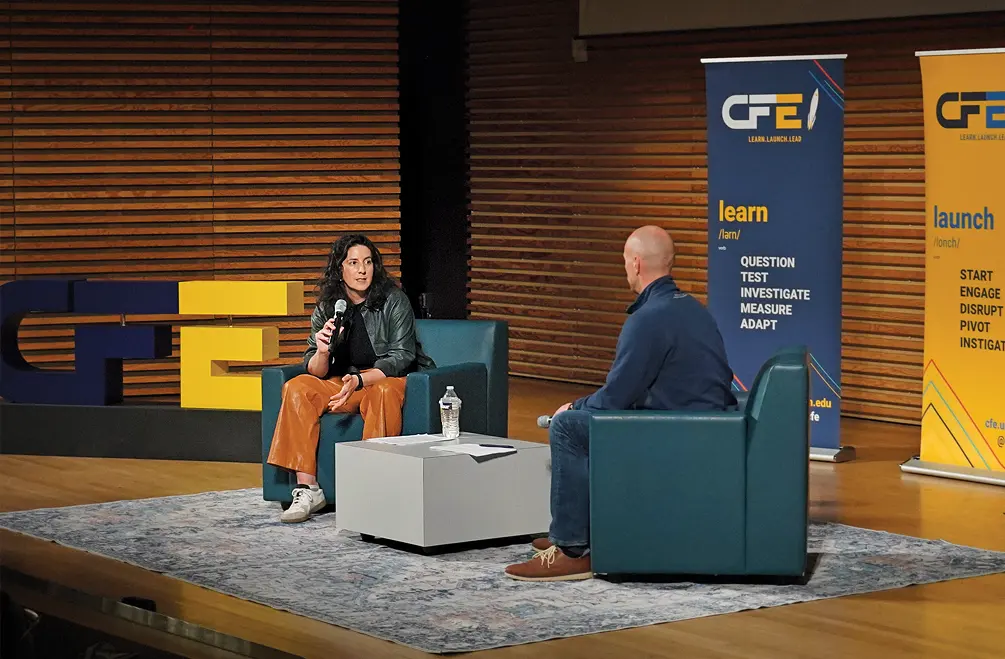 Candice Ammori, seated, talking with a host, also seated, on stage on campus in September as part of the Michigan Engineering Center for Entrepreneurship’s EHour speaker series.