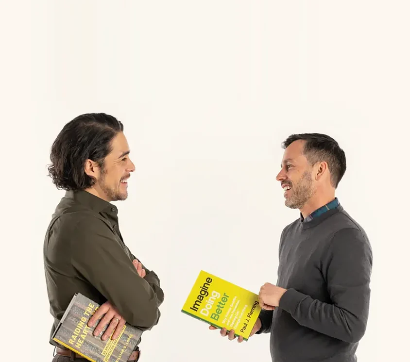 Bill Lopez, left, and Paul Fleming looking at each other, each holding a copy of their own books