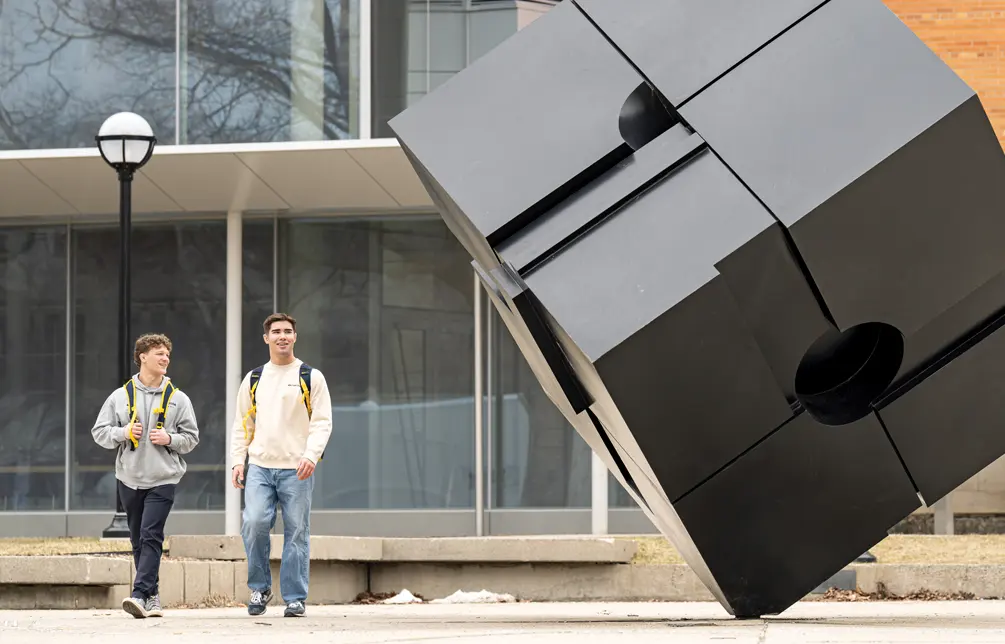 Knudten, right, and teammate Dylan Gilcher walk past 'The Cube' on campus
