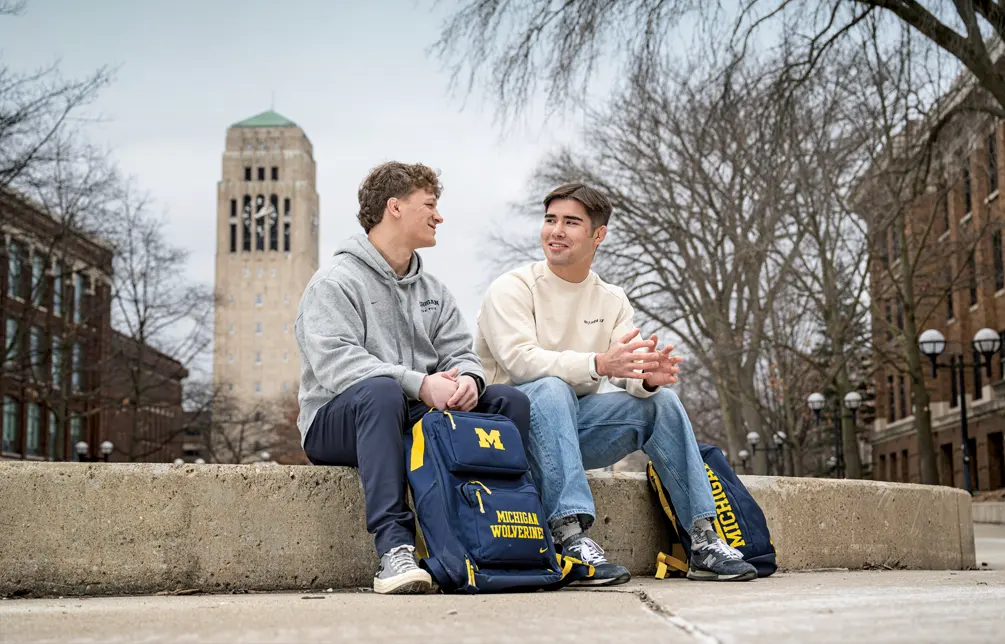 Josh Knudten, right, sit at the Diag on campus with the Burton Memorial Tower in the backgroundwith the 