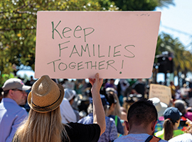 Demonstrators at a rally holding signs, one that reads "keep families together"