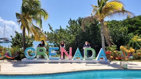 Group standing behind colored Grenada letters