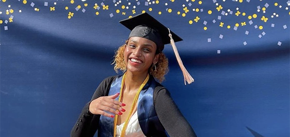 graduating student in front of congratulations sign