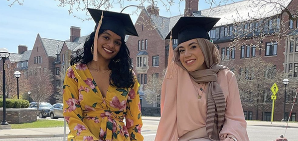 graduating students sitting on the school of public health sign