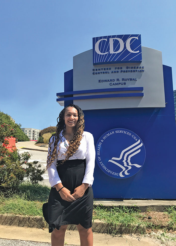 Jacqueline Cardoza standing in front of the sign for the Center for Disease Control and Prevention (CDC).