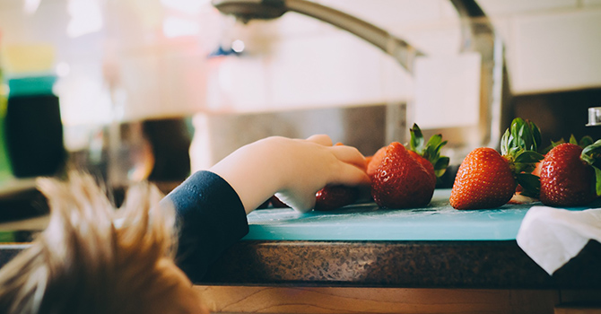 Child grabbing strawberries off of a counter