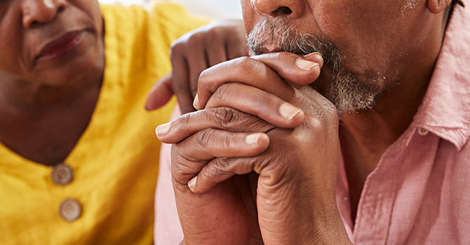 Two older adults sitting on a bench outdoors.