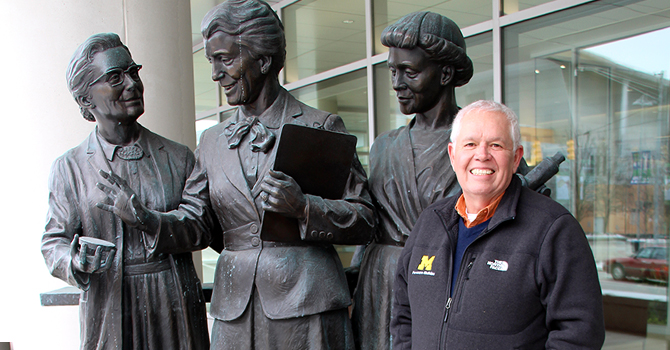 Matt Boulton standing with statue of Kendrick, Eldering, and Gordon in Grand Rapids