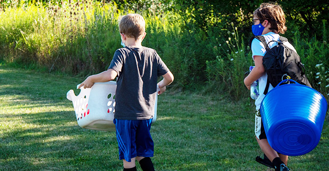 Two children walking in the grass to soccer practice.