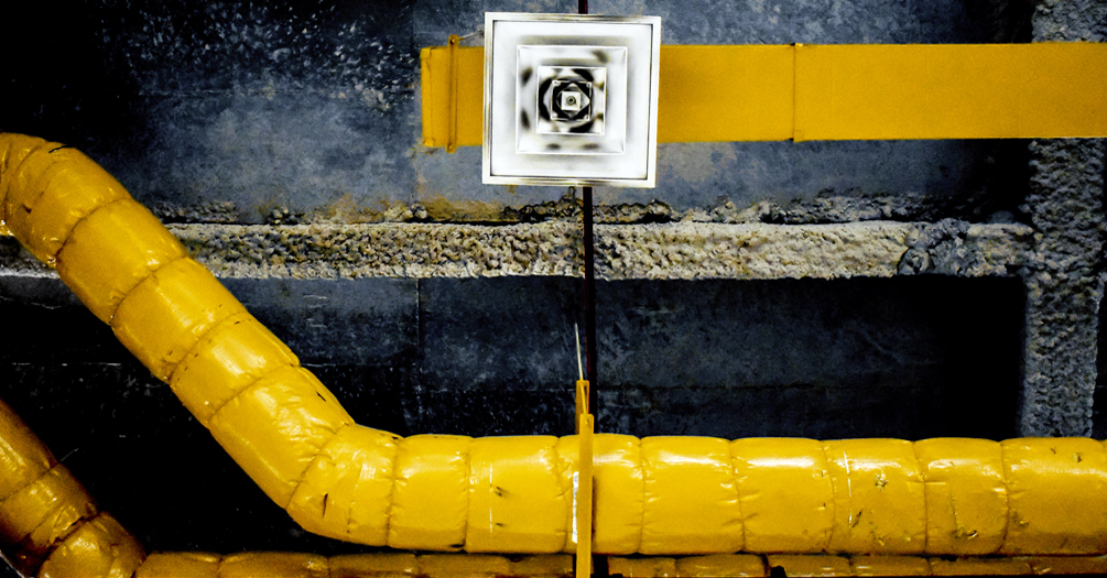 Yellow ventilation pipes on a ceiling.