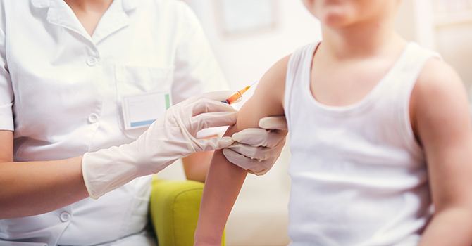 Child receiving a shot in the arm from a nurse.