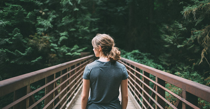 Woman on bridge in the forest.