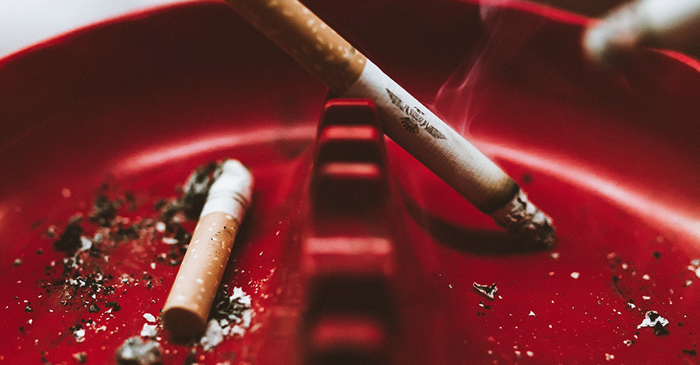 Cigarettes in a red ashtray.