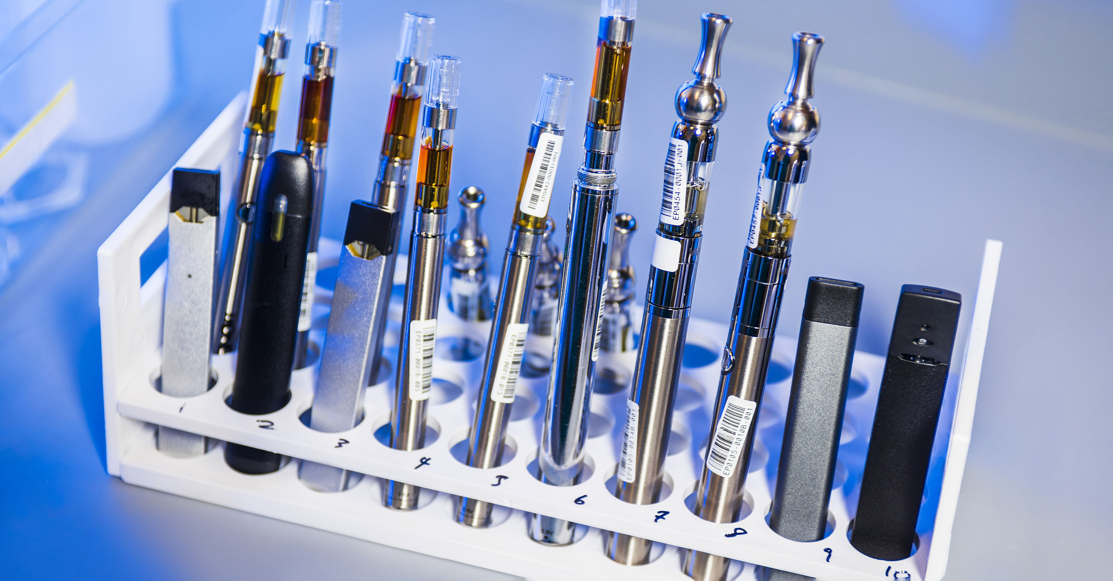 A series of vape pens in a stand for testing.