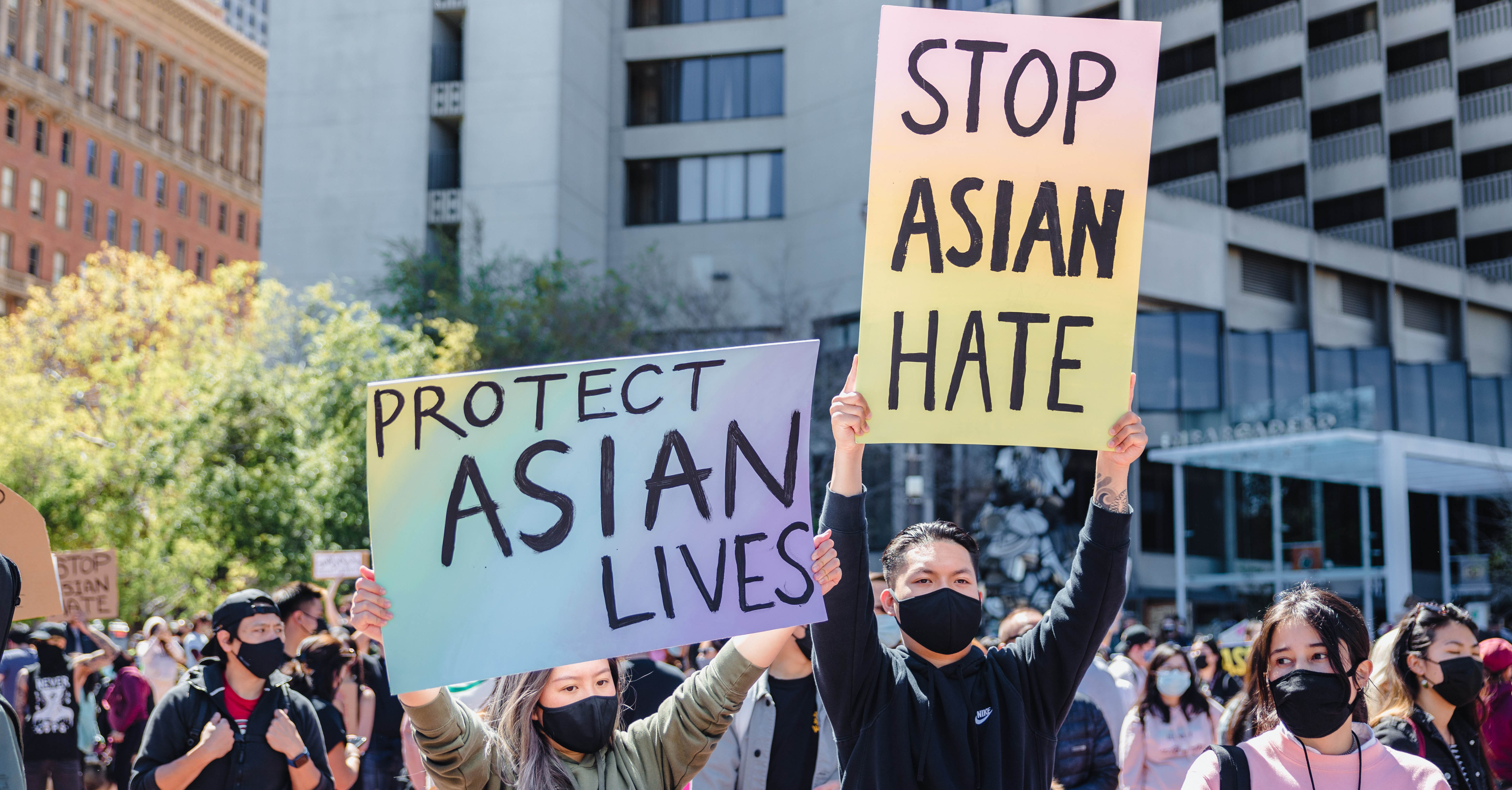 People stand outside with signs that say "stop Asian hate."