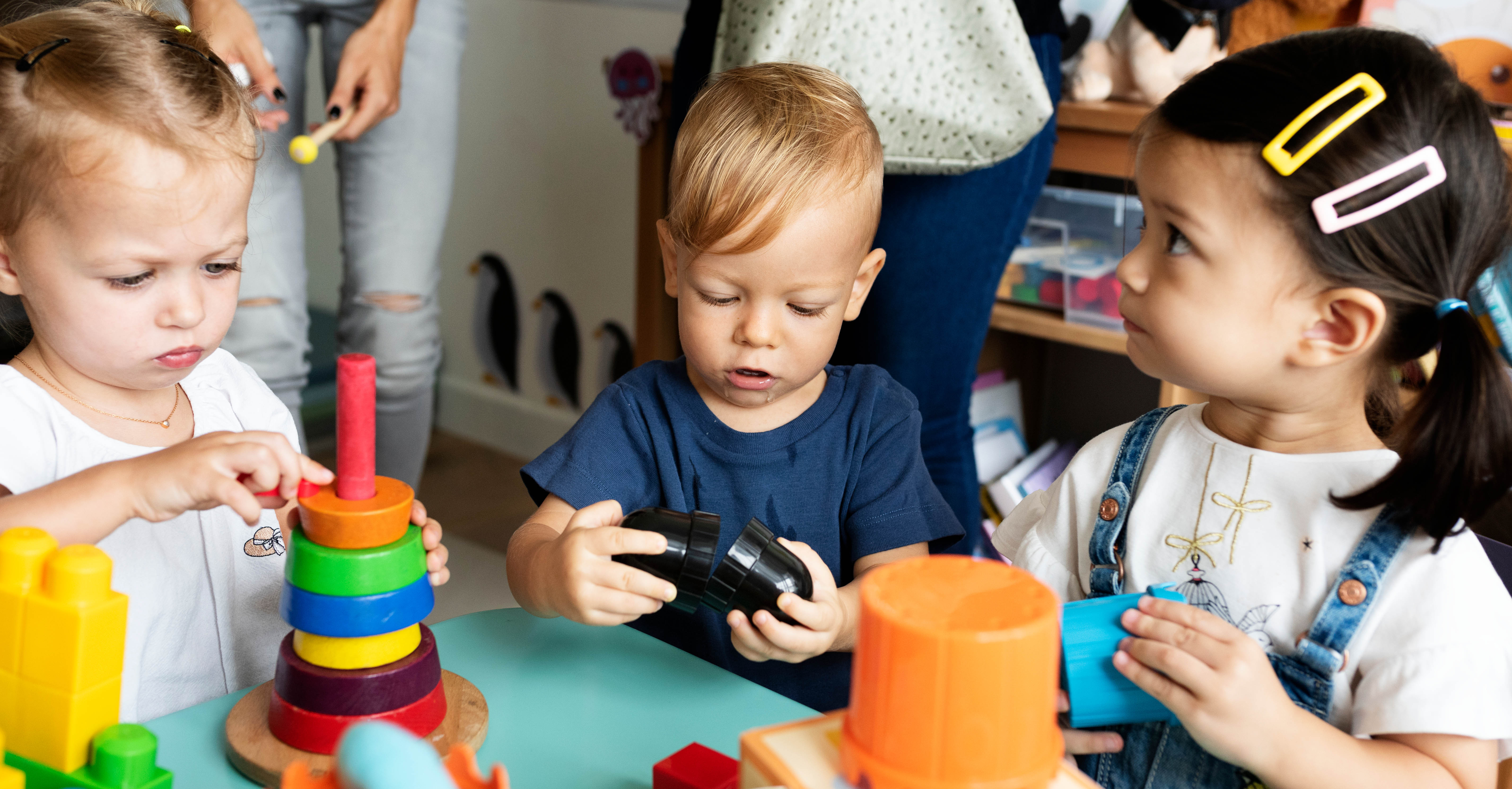 Three small children play at a table.