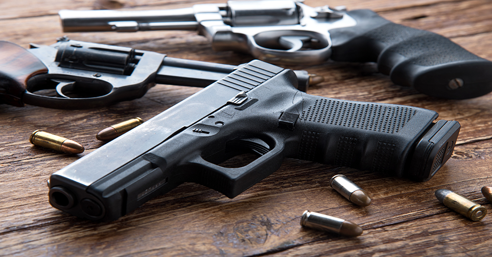 Firearms and ammo on a wooden table.