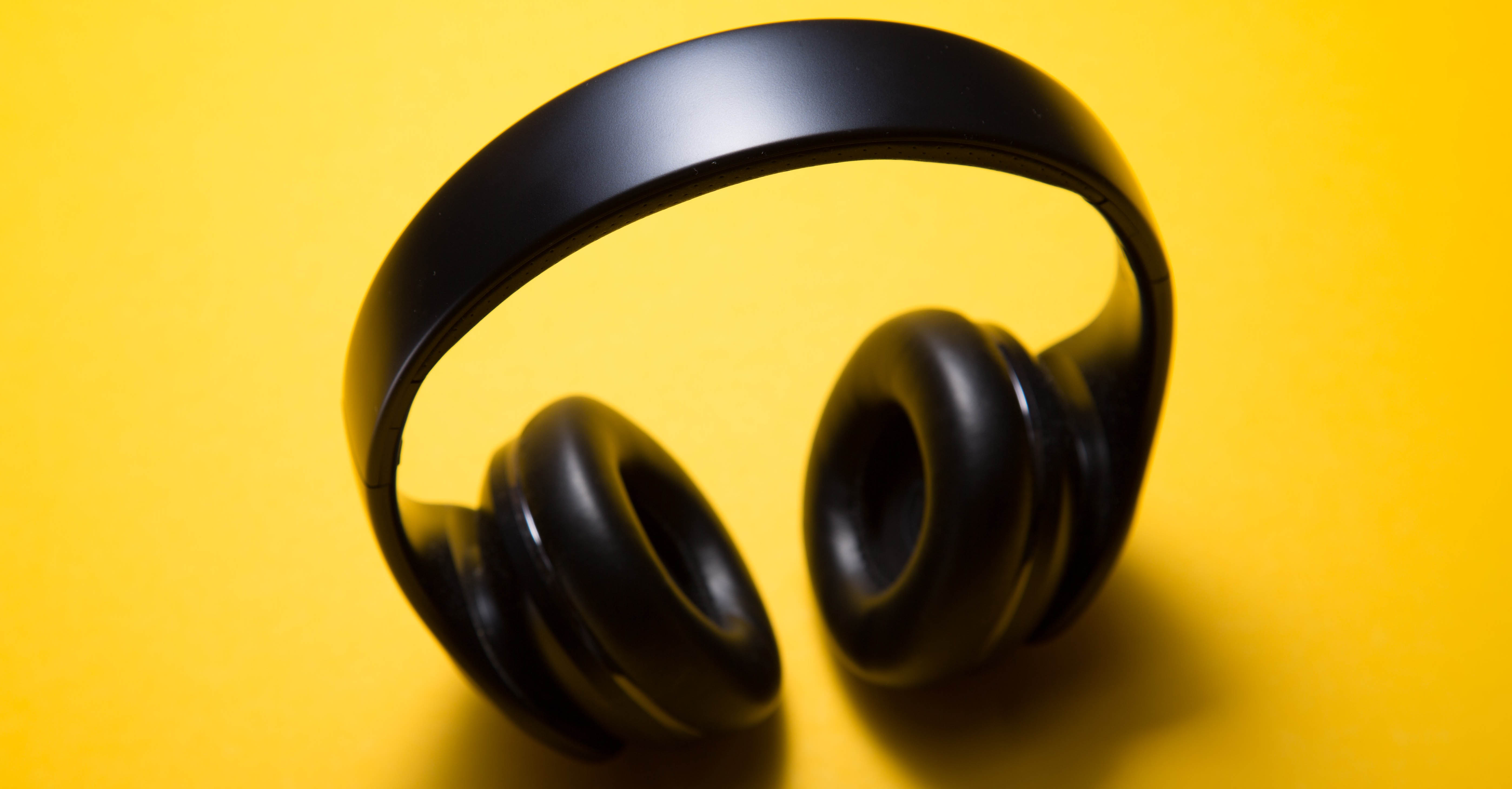 A pair of over-the-ear headphones on a yellow background.