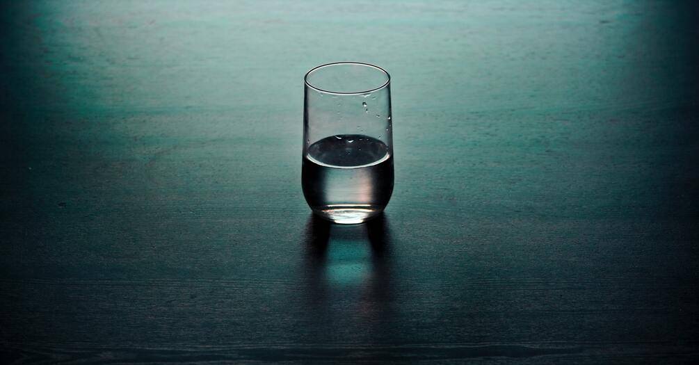 A glass, half full with water, on a table
