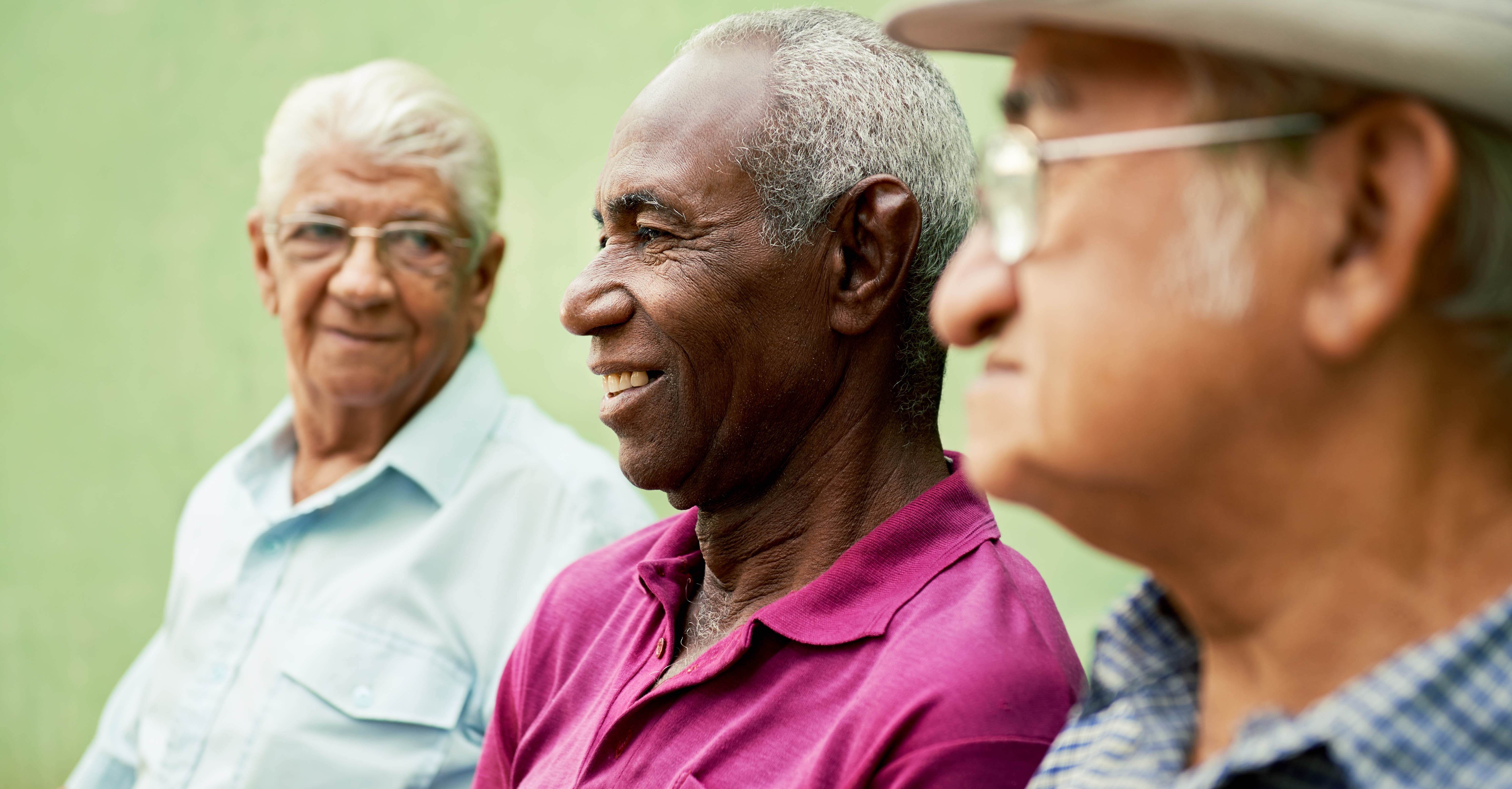 Three male older adults sit together.