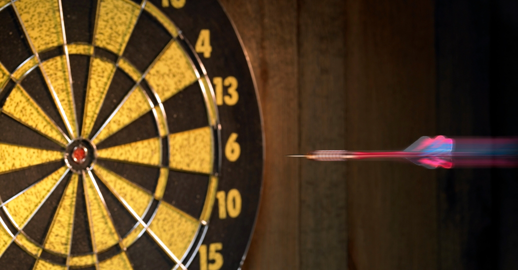 A dart is thrown toward a bullseye.
