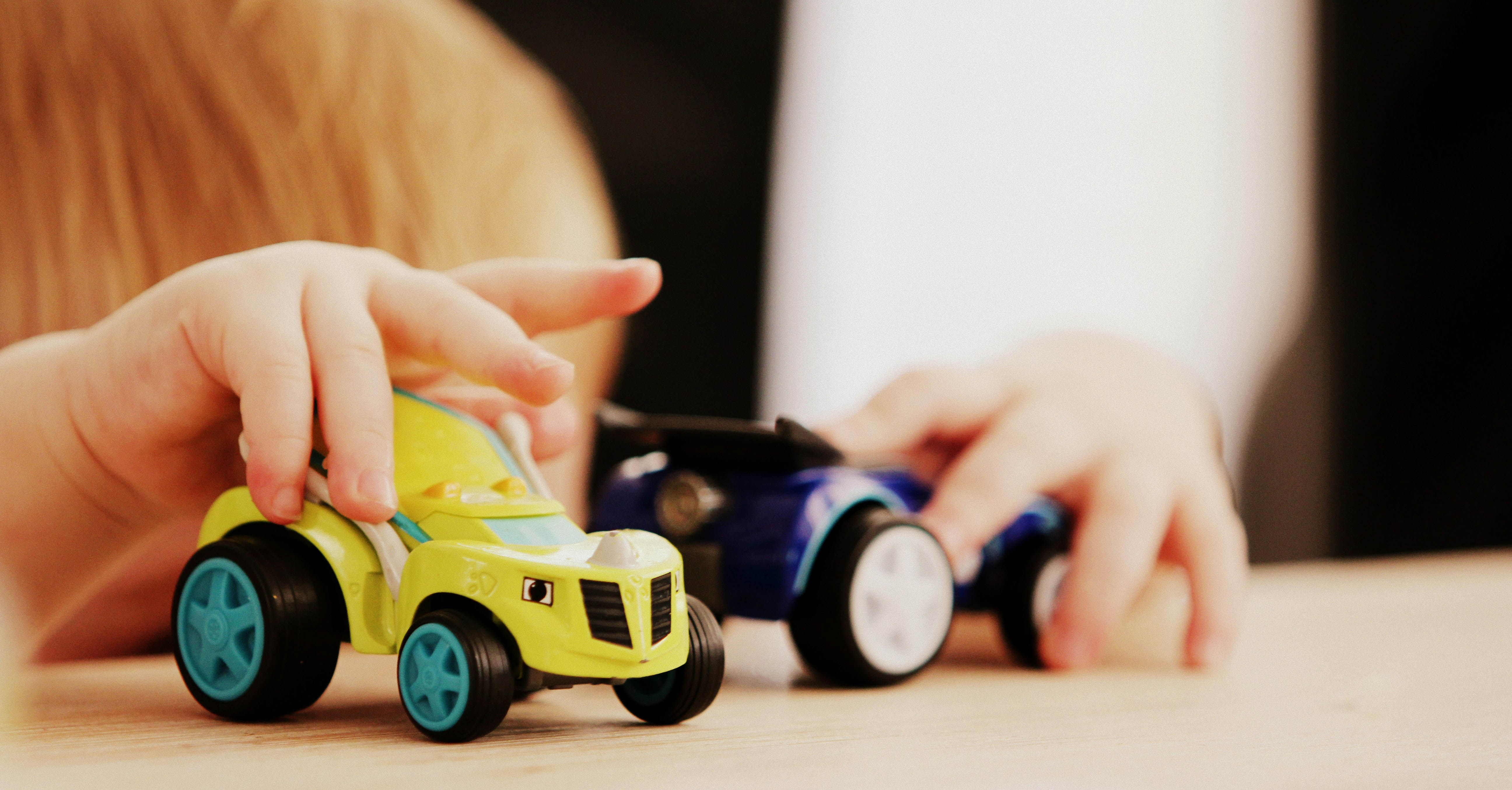 A child plays with toy cars on a table.