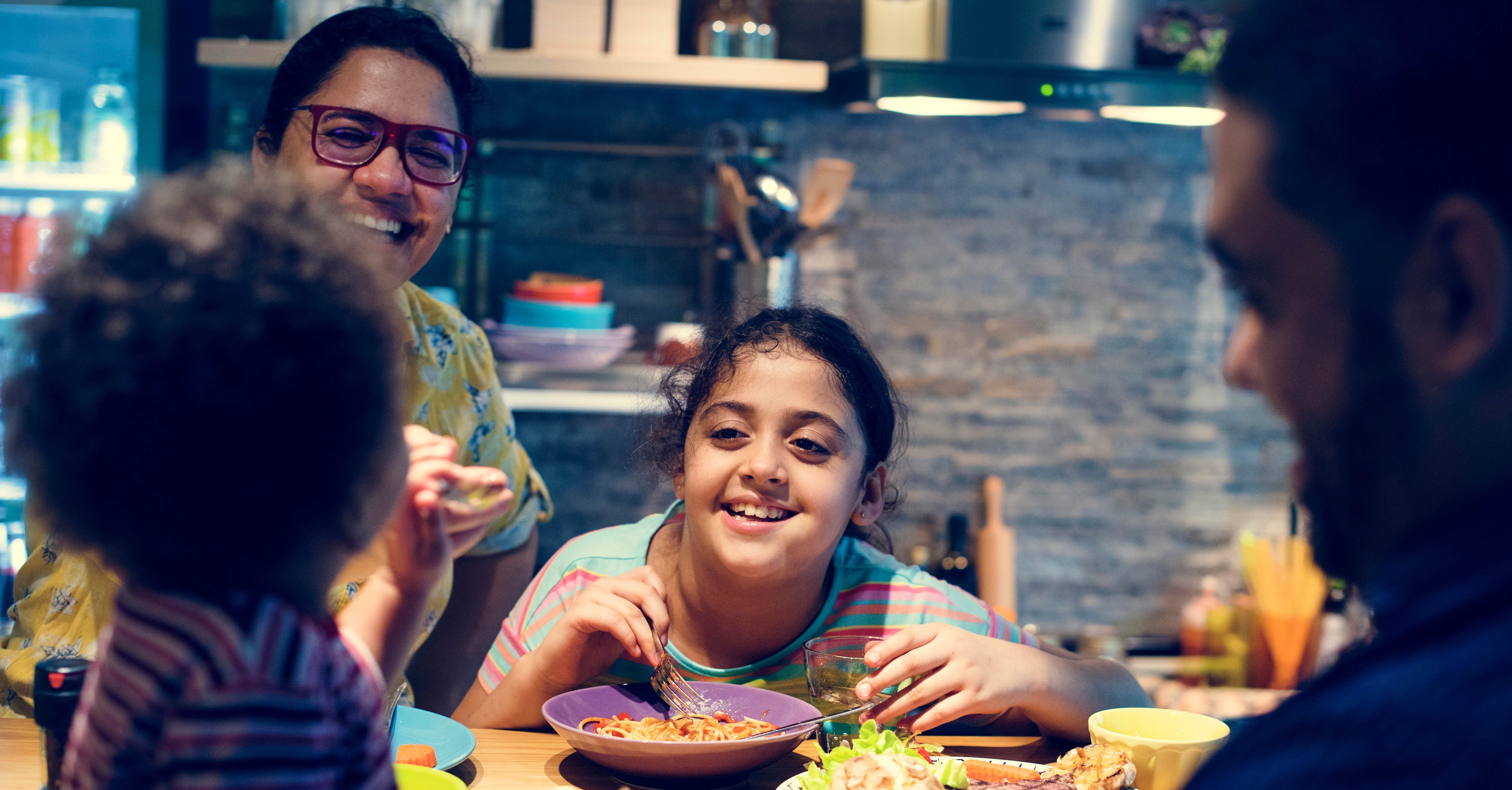 A family sits at a table while eating food.