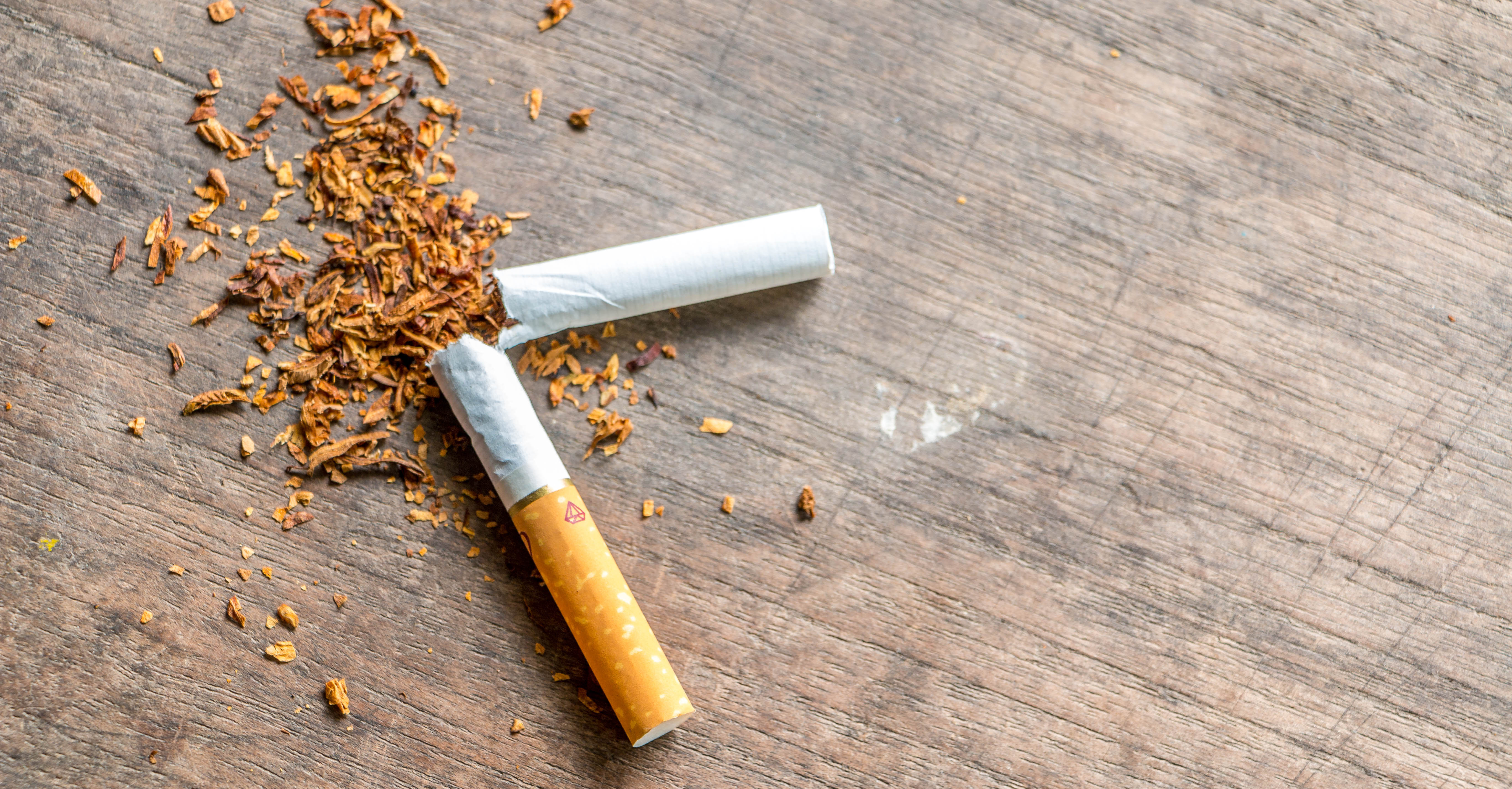 A broken cigarette on a wood surface. 