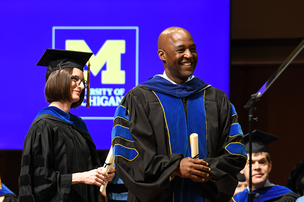 Dean F. DuBois Bowman, right, and Belinda Needham, chair of the Department of Epidemiology, greet graduates on the stage of Hill Auditorium.