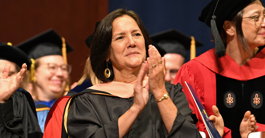 Kristen J. Sarri claps on stage for the Class of 2025.