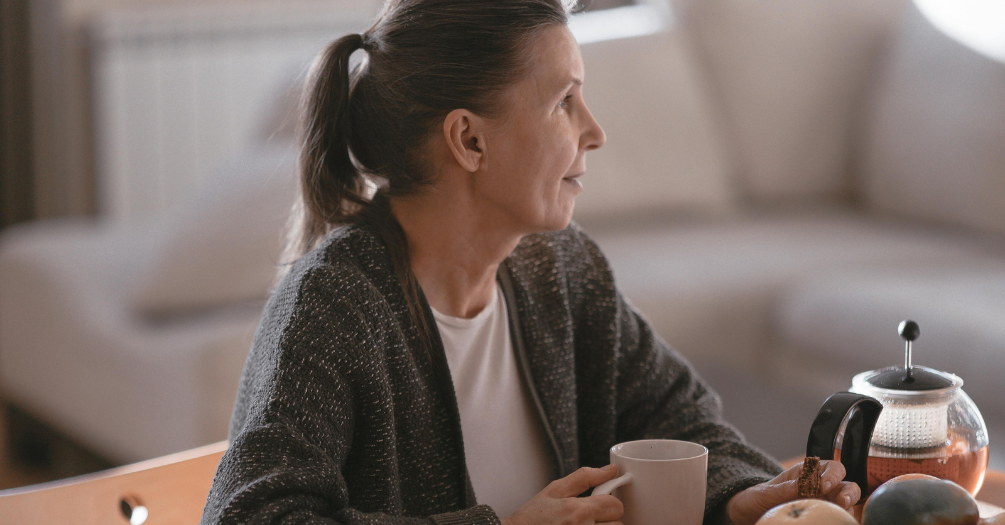 Older woman enjoying morning tea in her living room.