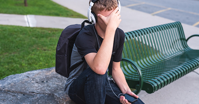 stressed teenage student sitting outside of school