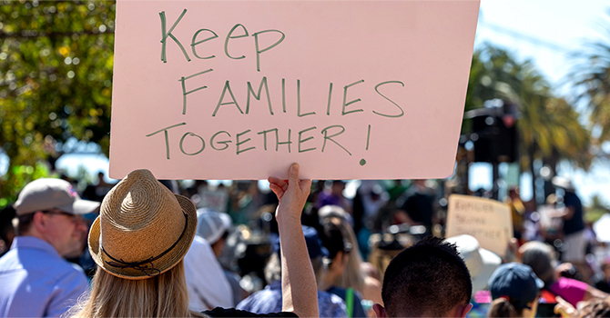 People holding a sign that says "Keep families together."