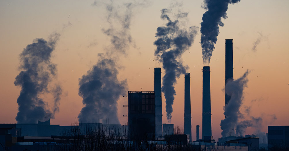 Smokestacks shooting steam into a morning lit sky.