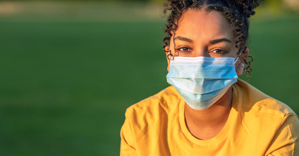 A teenager wearing a mask outside