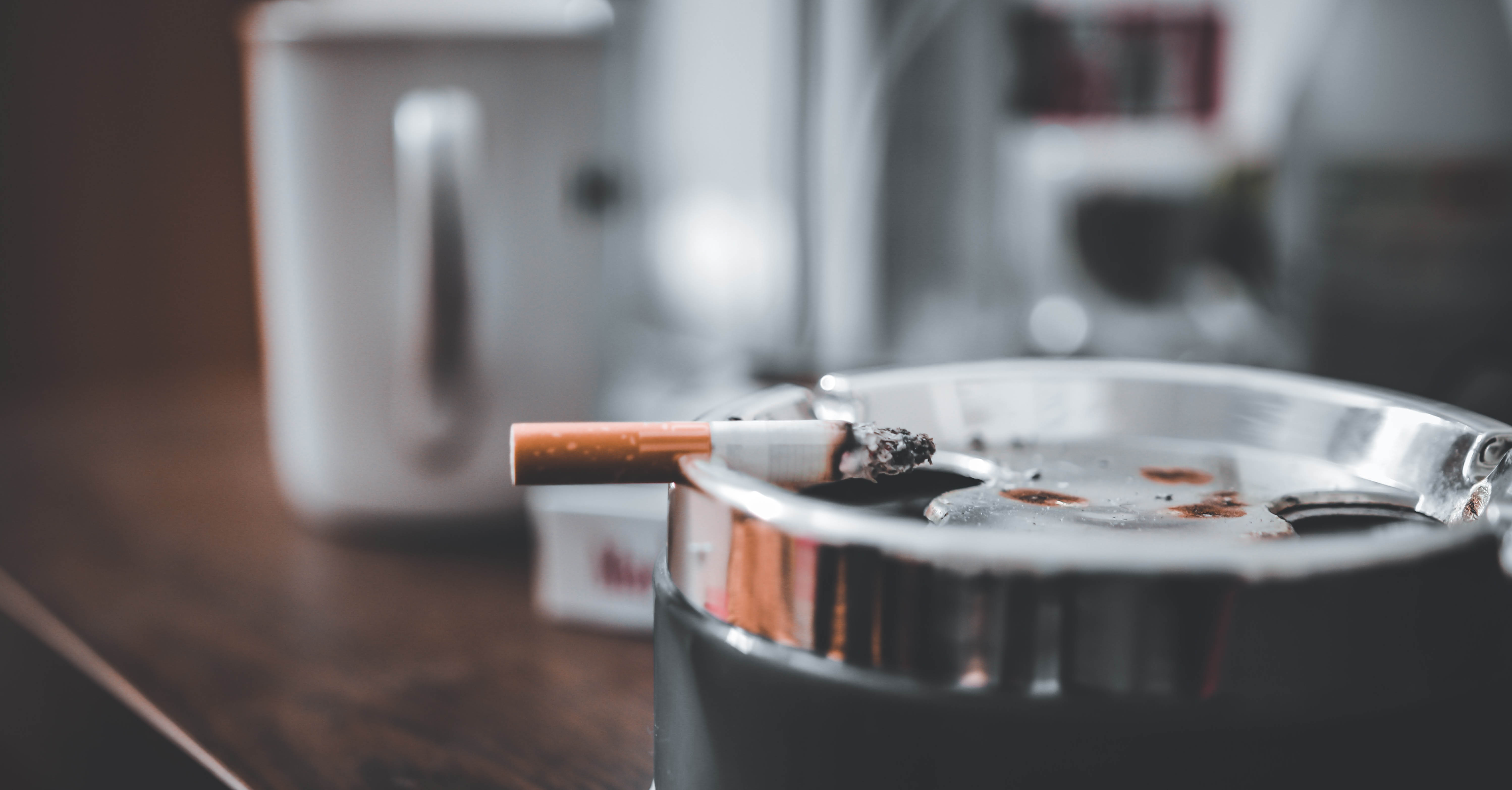 A burned cigarette sits on the edge of an ash tray.