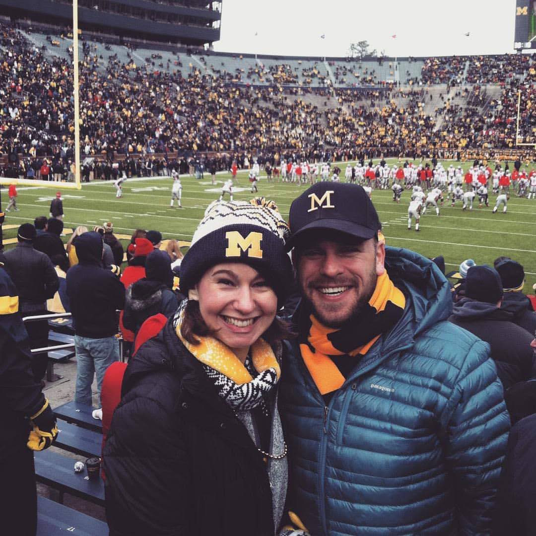 Jen and Matt at a football game wearing Michigan attire