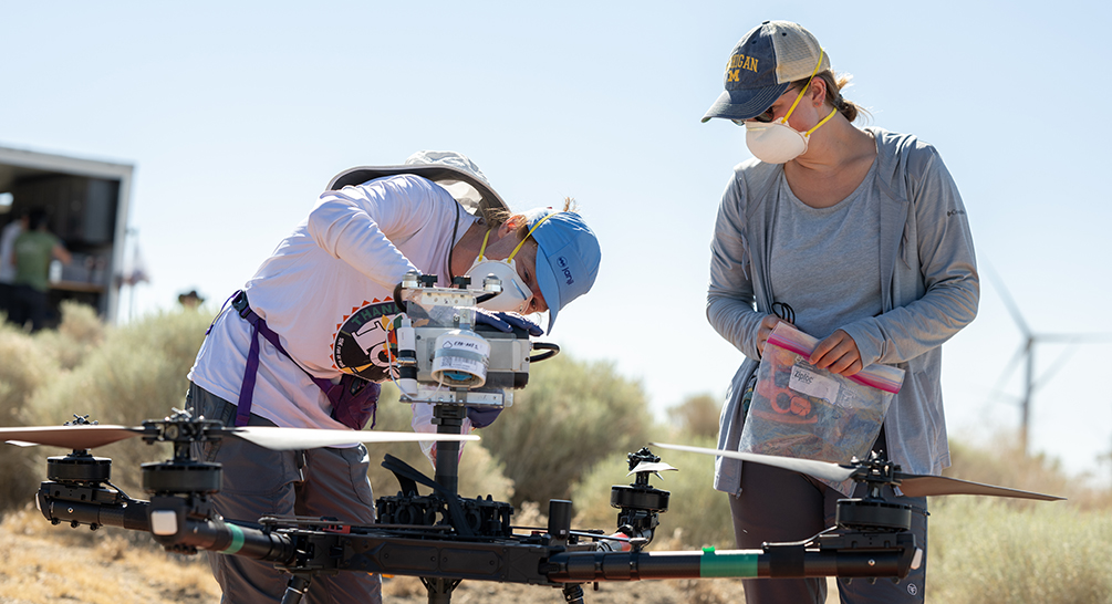 Jennifer Head, left, and student researcher Sarah Dobson load an air filter on a drone in order to sample air for Coccidioides.